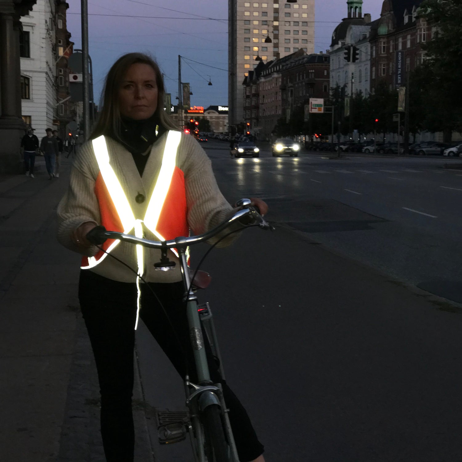 woman on bicycle in chic stylish reflective vest at night